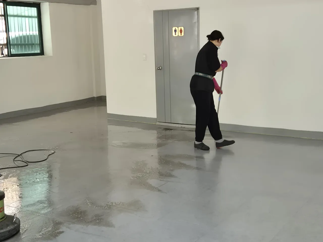 출입문 앞 바닥을 밀대로 닦는 작업자