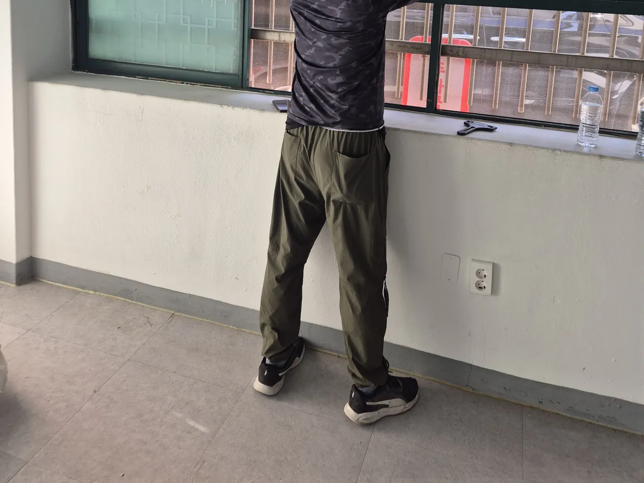 창문 위쪽을 손으로 닦거나 정리하는 작업자