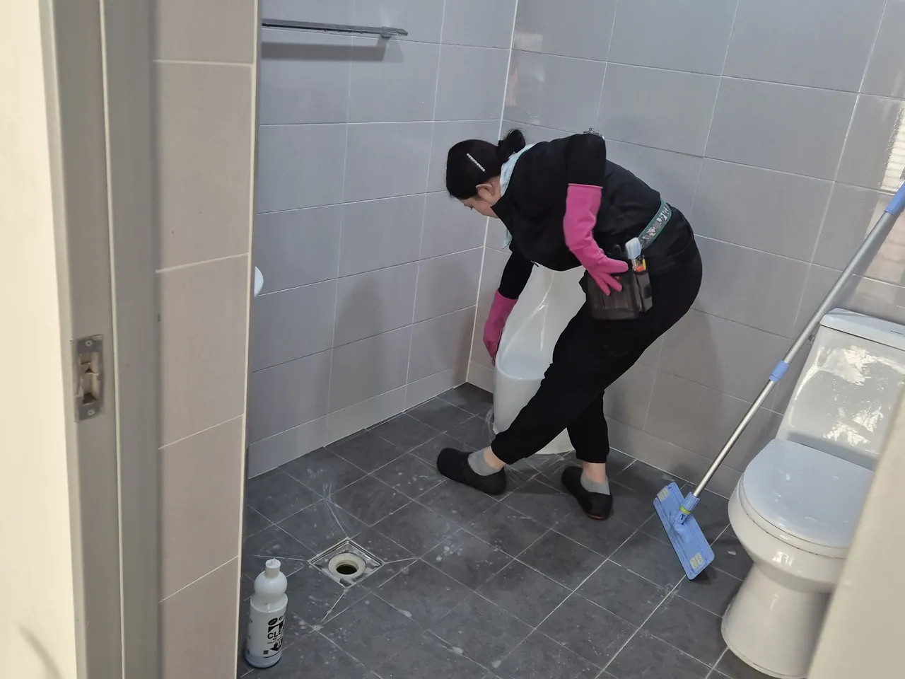 화장실 바닥 배수구 주변을 닦는 작업자